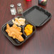 A black Genpak foam container with food in 3 compartments.