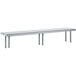 A stainless steel long rectangular table mounted shelf with legs.