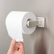 A person installing a Bobrick surface-mounted toilet tissue dispenser on a metal wall.