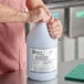 A person holding a white jug of Noble Chemical Bacti-Free Third Sink Sanitizer on a counter.