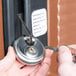 A person using a key to unlock a lock on a Cambro food pan carrier.