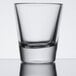 A close up of a Libbey shot glass with a clear surface and a reflection.