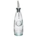 A clear glass Tablecraft oil and vinegar dispenser with a stainless steel pourer.