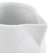 A CAC bright white porcelain creamer with a curved handle.