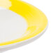 A close up of a yellow saucer with a white rim.