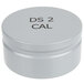 A gray metal Edlund container with black text reading "DS-2 Cal" containing a white Edlund calibration weight.