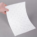 A person's hand holding a white Spilfyter heavy weight absorbent roll with holes in it.