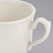 A close-up of a Homer Laughlin ivory china coffee cup with a handle.