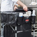 A chef putting a black cover on a Rubbermaid cart.