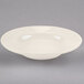 A Homer Laughlin ivory china soup bowl with a rolled edge on a gray surface.