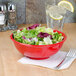 A red Thunder Group Pure Red melamine salad bowl on a table with salad in it.