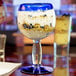 A Libbey round cocktail glass with cobalt blue accents filled with yogurt, granola, and berries on a table.