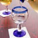 A close-up of a Libbey Aruba cocktail glass with cobalt blue accents on a table in a Mexican restaurant with liquid being poured into it.
