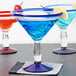 Three Libbey Aruba martini glasses with different colored drinks, including a blue drink with a lemon on the rim.