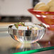 An American Metalcraft stainless steel serving bowl filled with food on a table.