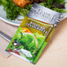 A Classic Gourmet Balsamic Vinaigrette portion packet on a plate of salad.