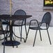 A black American Tables and Seating metal outdoor chair on a patio table.