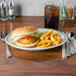 A Homer Laughlin green banded oval platter with a burger and a fork on a table.