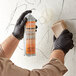 A person in black gloves using Noble Chemical Clean-It-Quick Vandalism Mark Remover to spray a wall.
