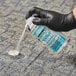 A person in black gloves using a spray can to remove gum from carpet.
