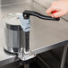 A hand using a Vollrath Redco can opener on a metal table.