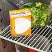 A box of Arm & Hammer Fridge-N-Freezer Baking Soda on a shelf in a refrigerator with a bowl of broccoli.