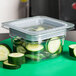 A clear plastic container of sliced cucumbers with a Cambro Clear Polycarbonate GripLid on it.