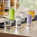 A table with several Acopa 1 oz. Shooter Glasses filled with purple liquid.