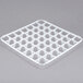 A white plastic grid with square compartments and holes.