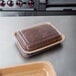 A brownie in a brown paperboard container with a clear lid.