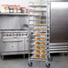 A large stainless steel Regency sheet pan rack with trays of baked goods on it.
