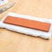 A knife on a towel being sharpened with a brown sharpening stone.