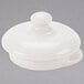 A white ceramic lid with a small knob on top over a white round object.