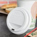A Solo white plastic dome lid with a sip hole on a white coffee cup on a counter.
