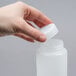 A hand holding a white plastic FIFO Innovations squeeze bottle.