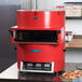A TurboChef fire red electric countertop ventless pizza oven on a counter with a pizza inside.