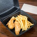 A Dart black foam square takeout container with food in it.