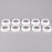 A row of six white plastic Tablecraft salad dressing dispenser collars with beige lettering.