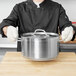A chef wearing heat-resistant gloves holding a pot.