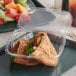 A Dart ClearPac plastic container with a sandwich, fruit, and tortilla inside.