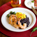 A close-up of a Tuxton Colorado white narrow rim plate with shrimp, black beans, and rice.