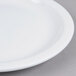 A close up of a Tuxton Colorado bright white narrow rim china plate on a gray surface.