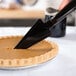 A Visions black plastic knife cutting a pie.