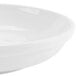 A close up of a CAC Super Bright White porcelain salad bowl with a shadow on a white surface.
