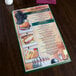 A green Hamilton heat sealed menu board on a table.