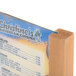 A Menu Solutions oak wood table tent holding a menu on a wooden stand.