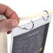 A hand holding a Menu Solutions almond wood flip top table tent menu card.