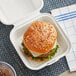 A hamburger in an EcoChoice bagasse takeout container on a table.