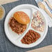A EcoChoice bagasse plate with a pulled pork sandwich, beans, and coleslaw.