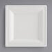 A white square EcoChoice Bagasse plate on a gray surface.